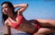 A woman in a red bikini laying on the beach.