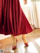 A woman in a red dress is standing on a wooden floor.