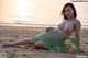 A woman in a green dress sitting on the beach.