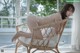 A woman in a white bikini sitting on a wicker chair.