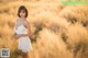 A woman in a white dress standing in a field of tall grass.