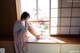 A woman sitting on a window sill looking out a window.